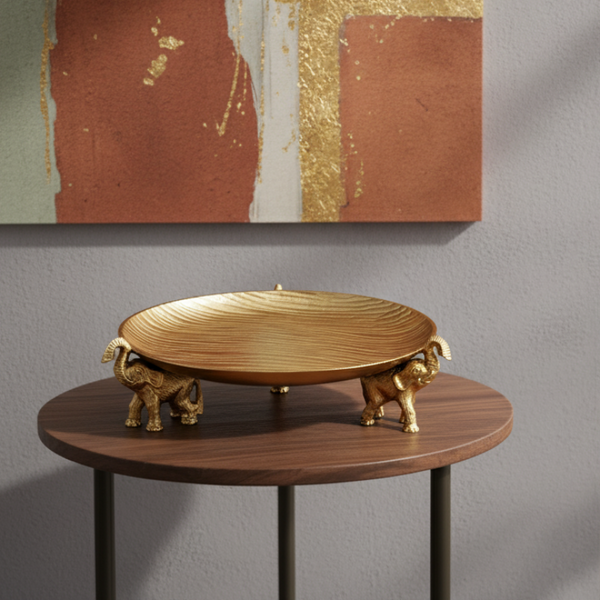 Gold decorative dish on a wooden table with abstract art in the background