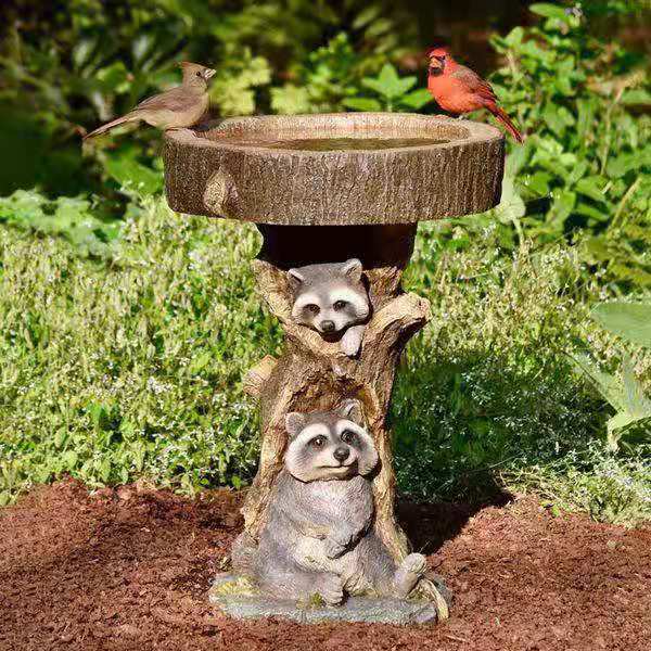 A delightful garden ornament featuring a small raccoon by a bird bath, crafted from resin to add a charming touch to your outdoor decor.